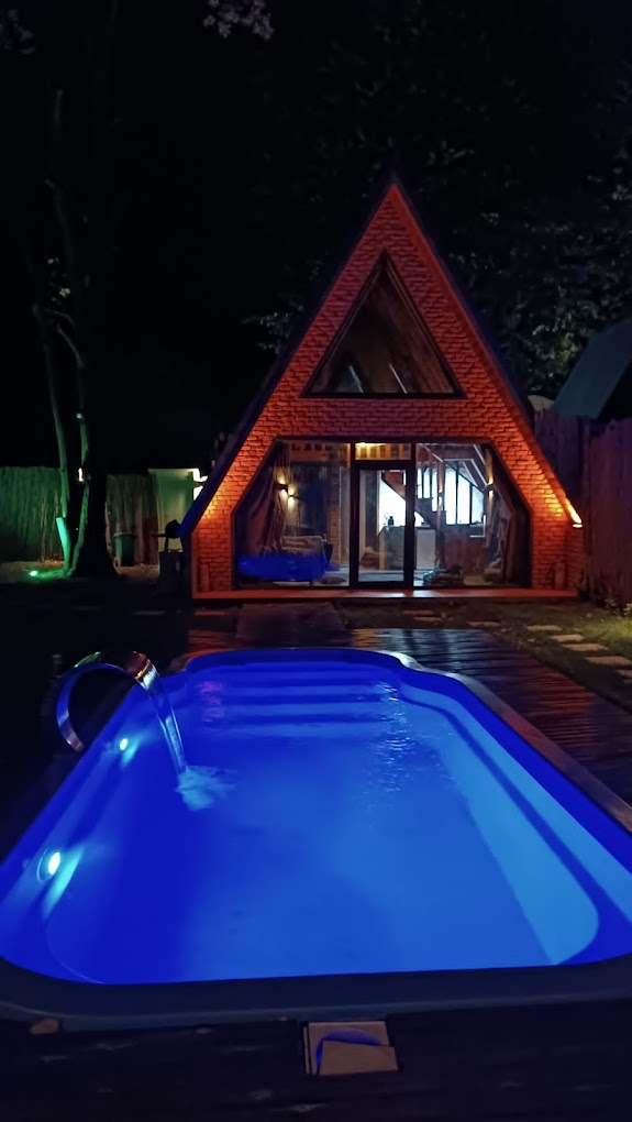 Gece aydınlatmalı yüzme havuzu ve ışıklandırılmış A-frame bungalov